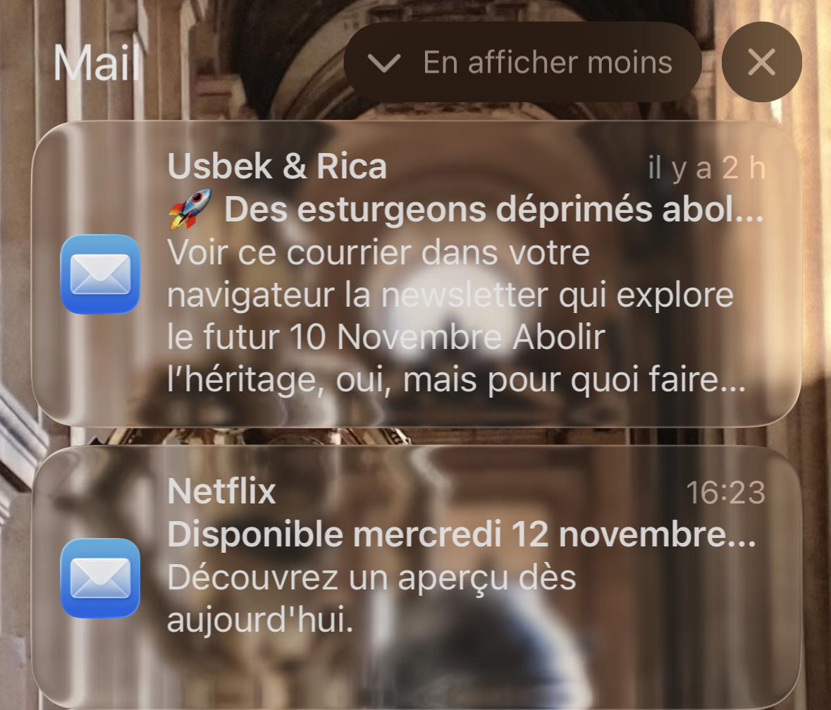 Deux notifications mail sont affichés, on discerne à peine le texte blanc avec un fond transparent, façon <span lang="en">Liquid Glass</span>. En arrière plan, mon fond d'écran en photo avec deux robots.