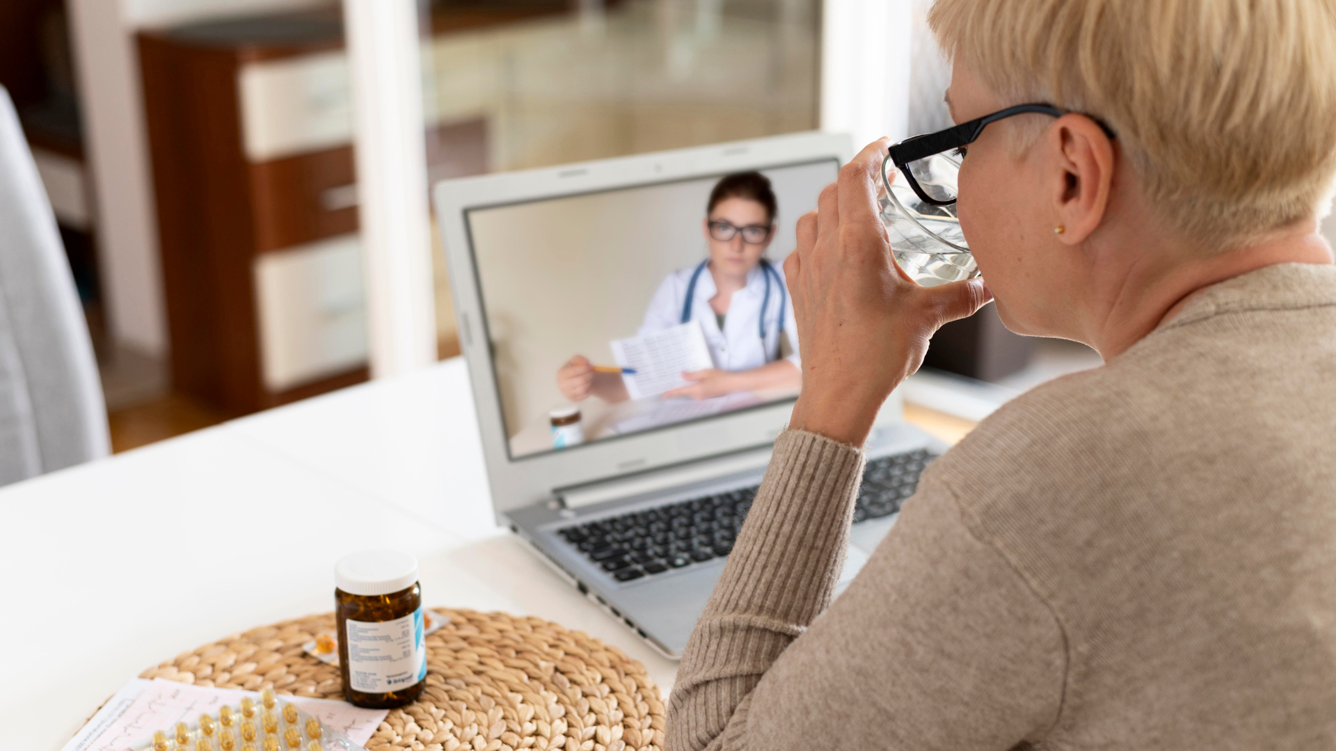 femme âgée en téléconsultation devant son ordinateur, son médecin lui montre un papier pour tester sa vision. La patiente a l'air détendue, confiante.