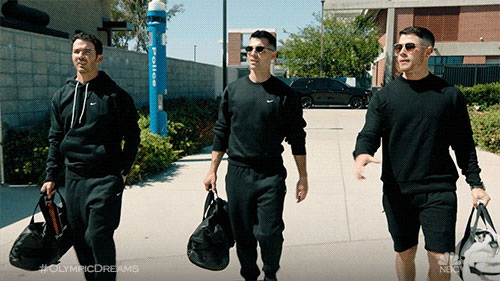 Les Jonas Brothers avec des survêtements noirs et sacs de sport