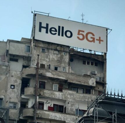 Un panneau publicitaire pour la 5G en haut d'un immeuble vétuste. Contraste saisissant.